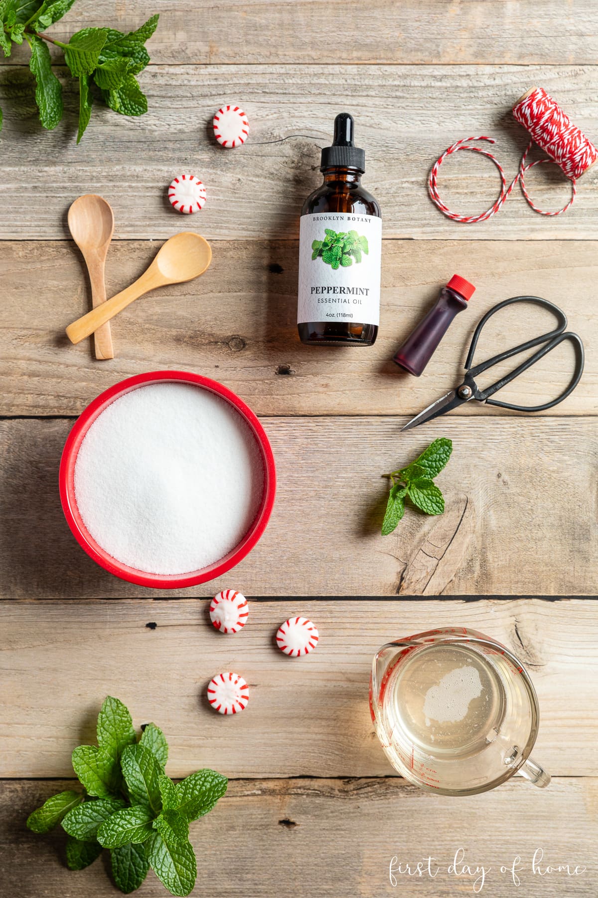 Ingredients for peppermint sugar scrub, including granulated white sugar, melted coconut oil, Peppermint Essential Oil, and optional red food coloring.