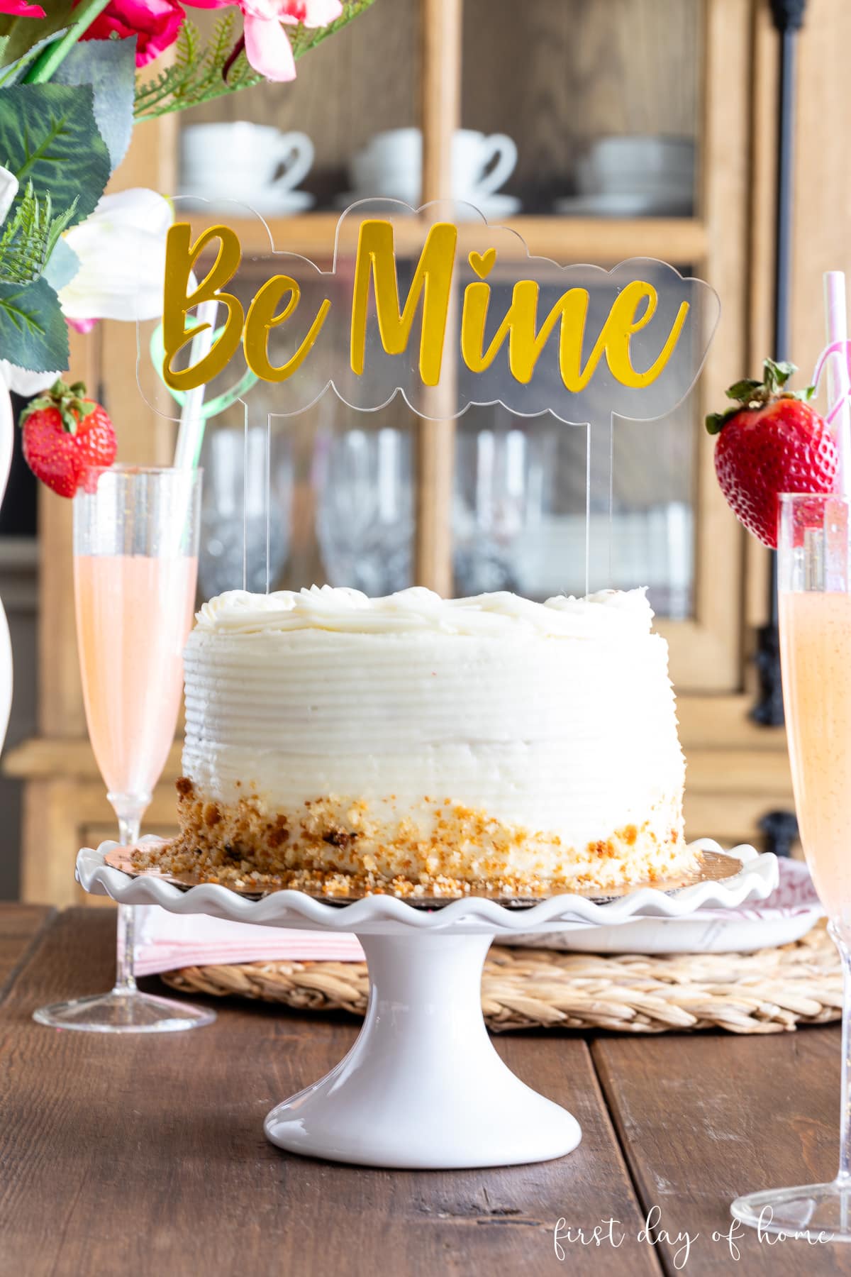 Cake on pedestal with laser cut acrylic cake topper that reads "Be Mine".