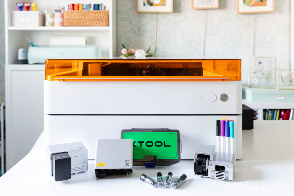 xTool M1 Ultra craft machine on desk, shown with accessories like pens, an ink module, laser module, and blades.