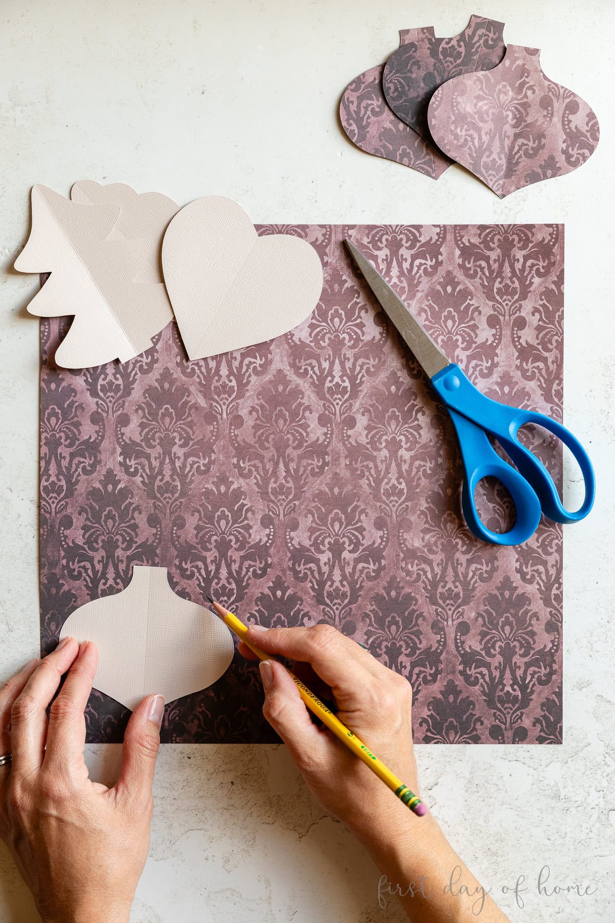 Tracing and cutting the paper Christmas ornament pattern on scrapbook paper.
