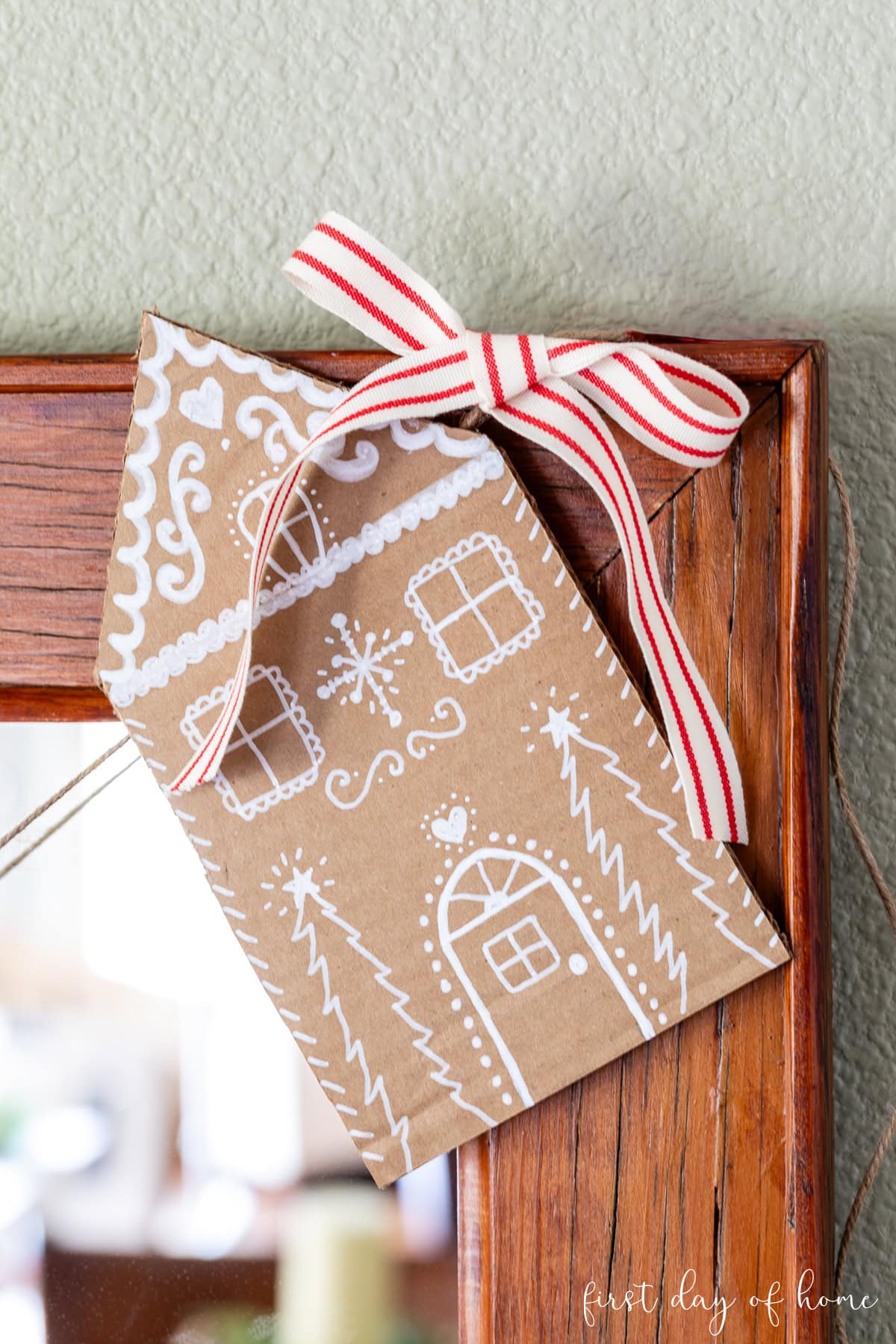 Cardboard gingerbread house hanging on a garland.