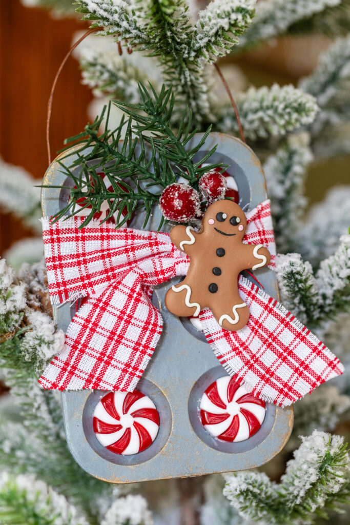 Gingerbread ornament with mini muffin tin, greenery, and ribbon.