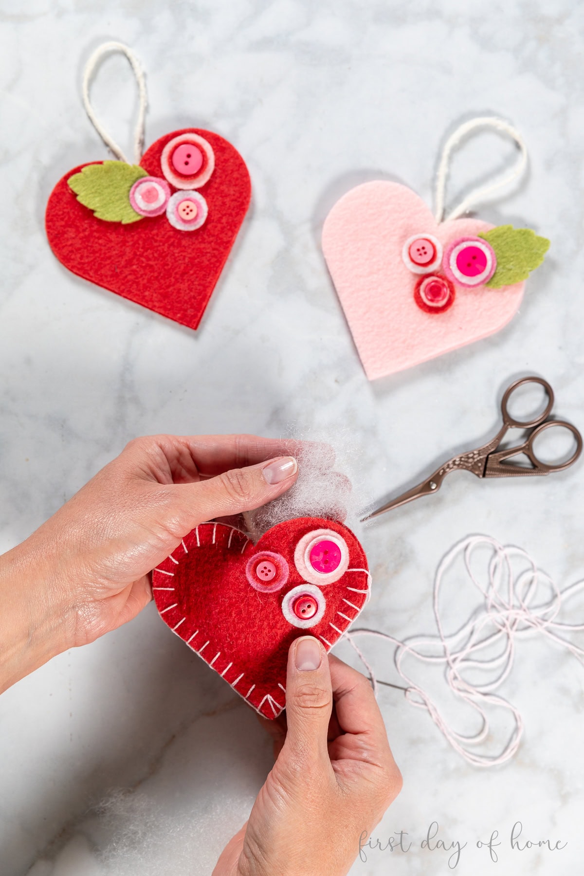Stitching the edges of the felt heart ornament and stuffing it with fiber fill.