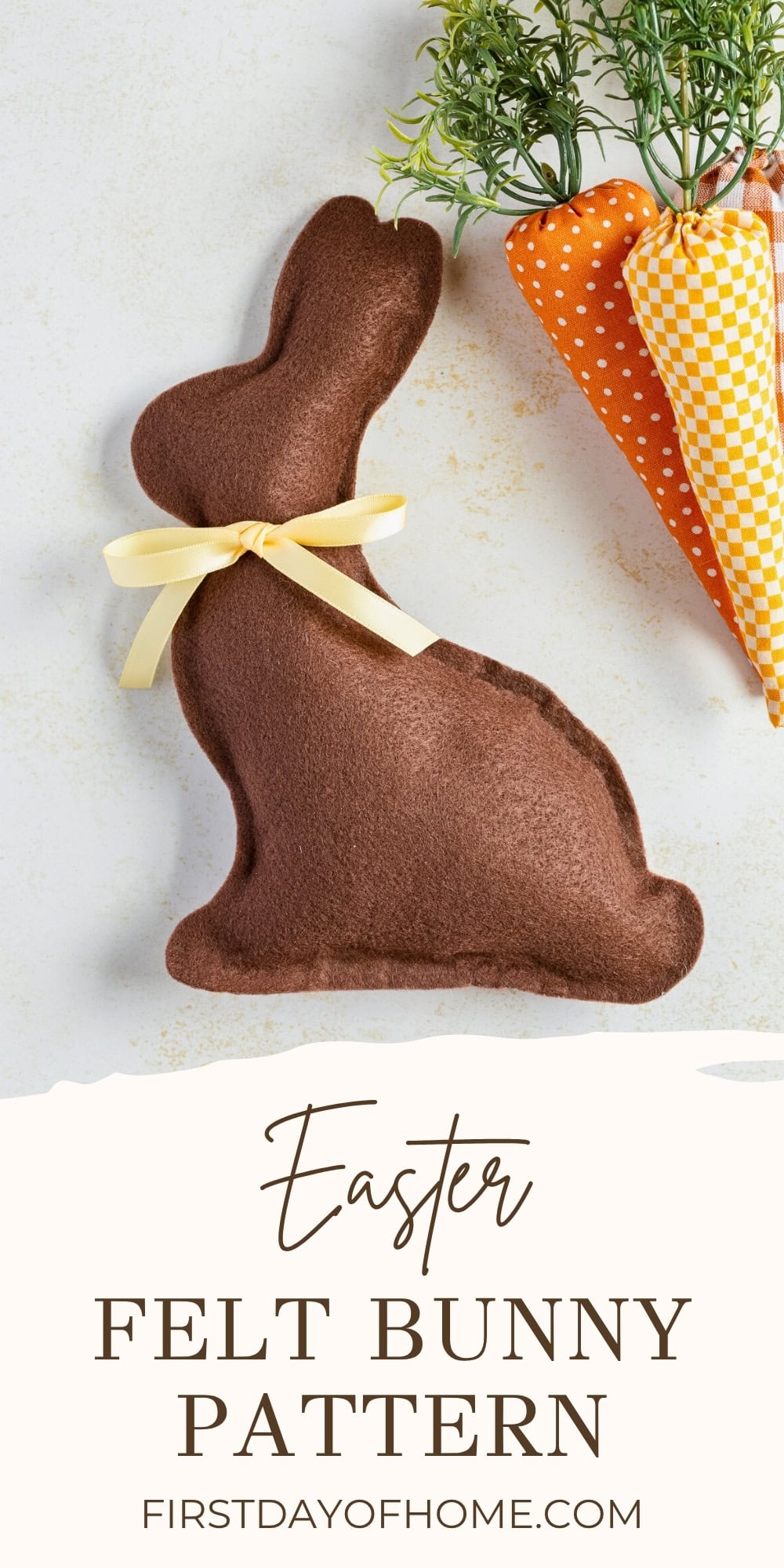 Felt bunny with yellow ribbon around its next shown with fabric carrots.