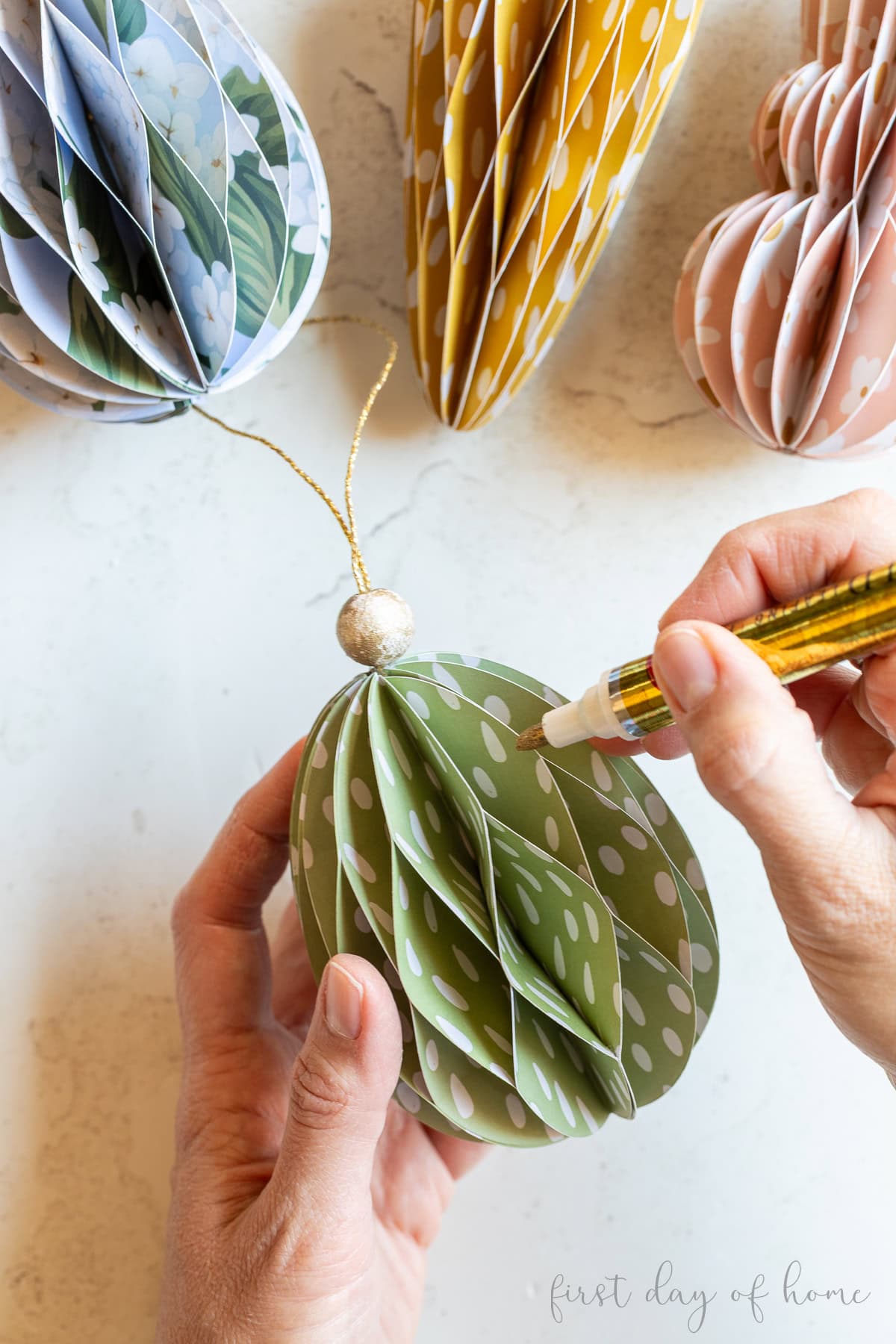 Adding gold leafing on the edges of an Easter egg ornament.