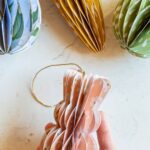 Hand holding a paper Easter ornament in the shape of a bunny.