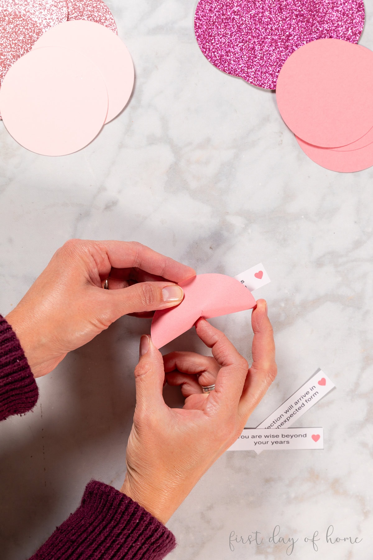Folding a paper circle to bend it into a fortune cookie shape.