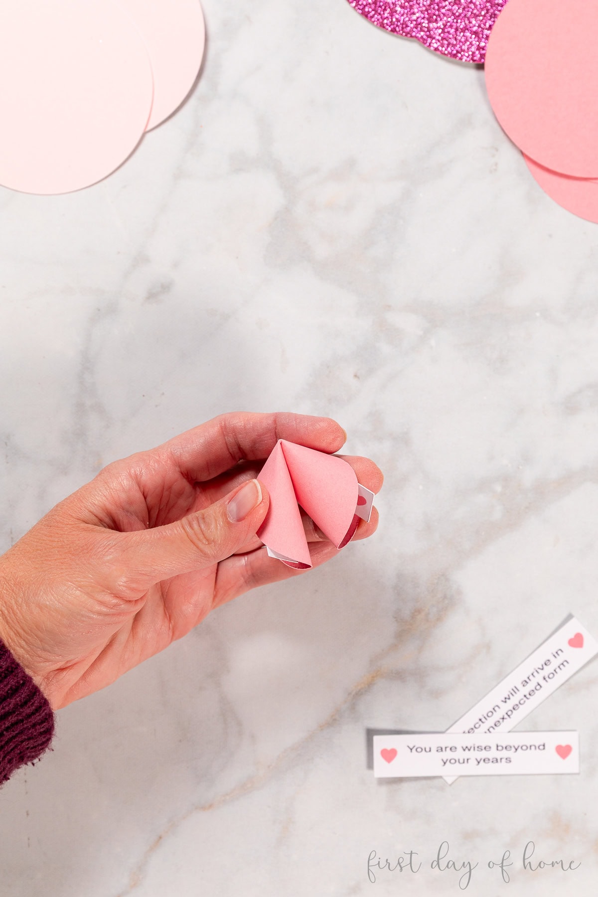 Folded paper fortune cookie in hand.
