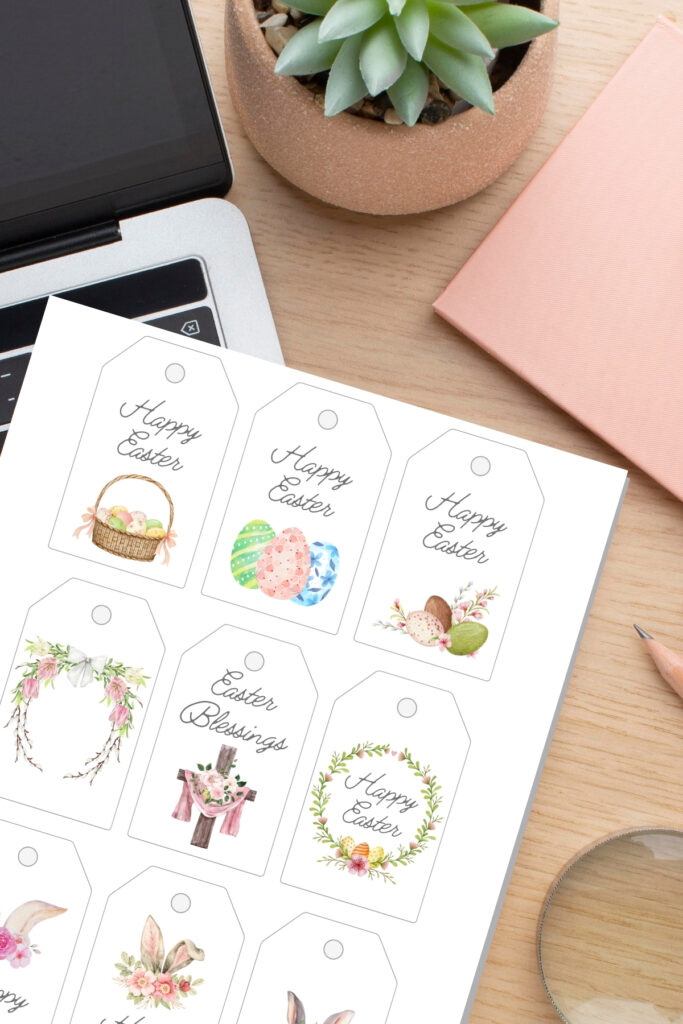 Printed sheet of Easter gift tags next to laptop and plant.