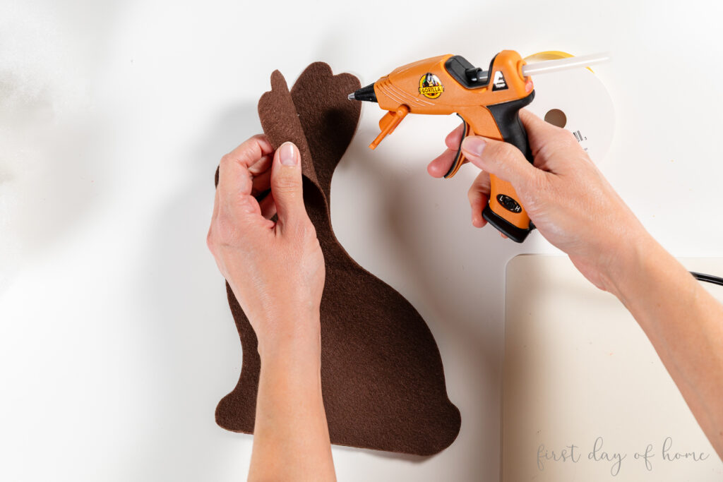 Gluing the edge of a felt bunny shape to make a plush felt Easter bunny.