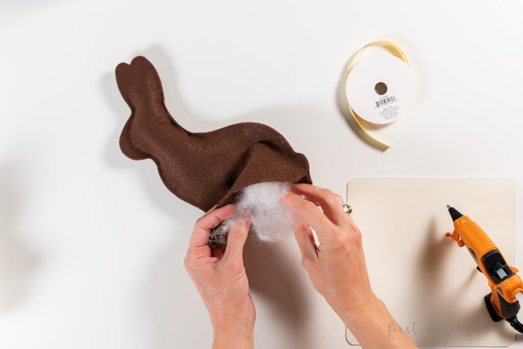 Stuffing a plush felt bunny with fiber fill.