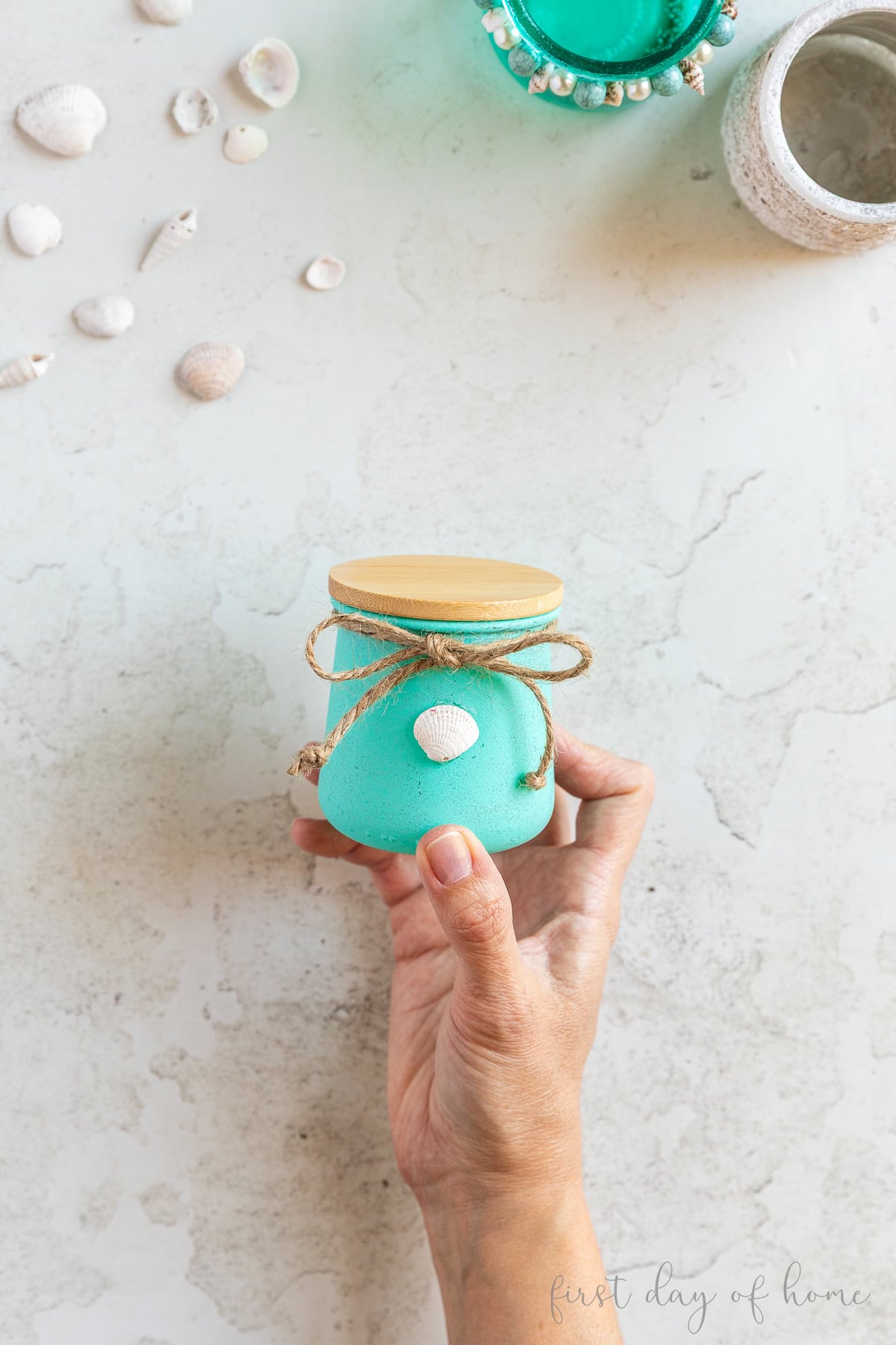 Painted glass jar decorated with a seashell and jute twine.