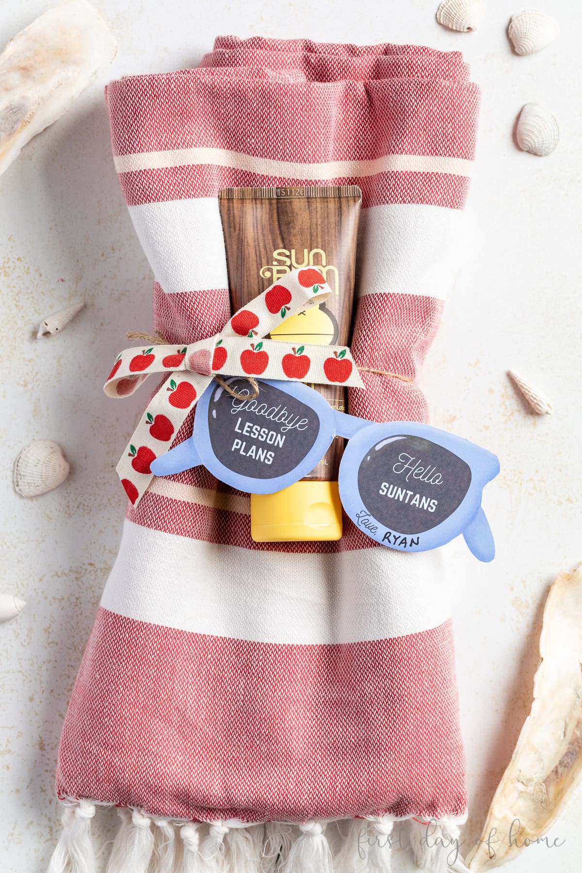Teacher appreciation gift with a Turkish beach towel, sunblock, and printed gift tags in the shape of sunglasses.