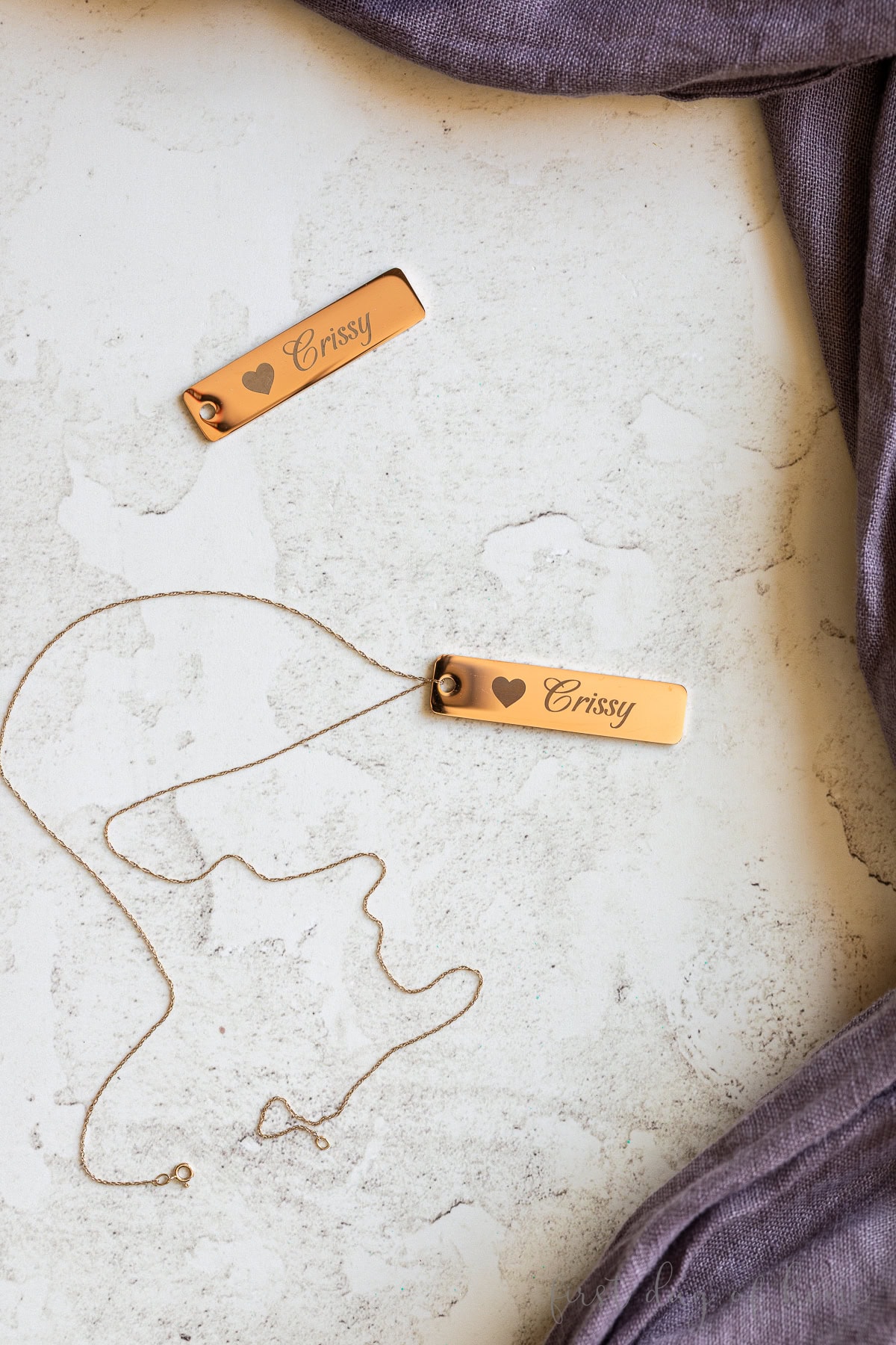 Laser engraved metal tags shown as jewelry.
