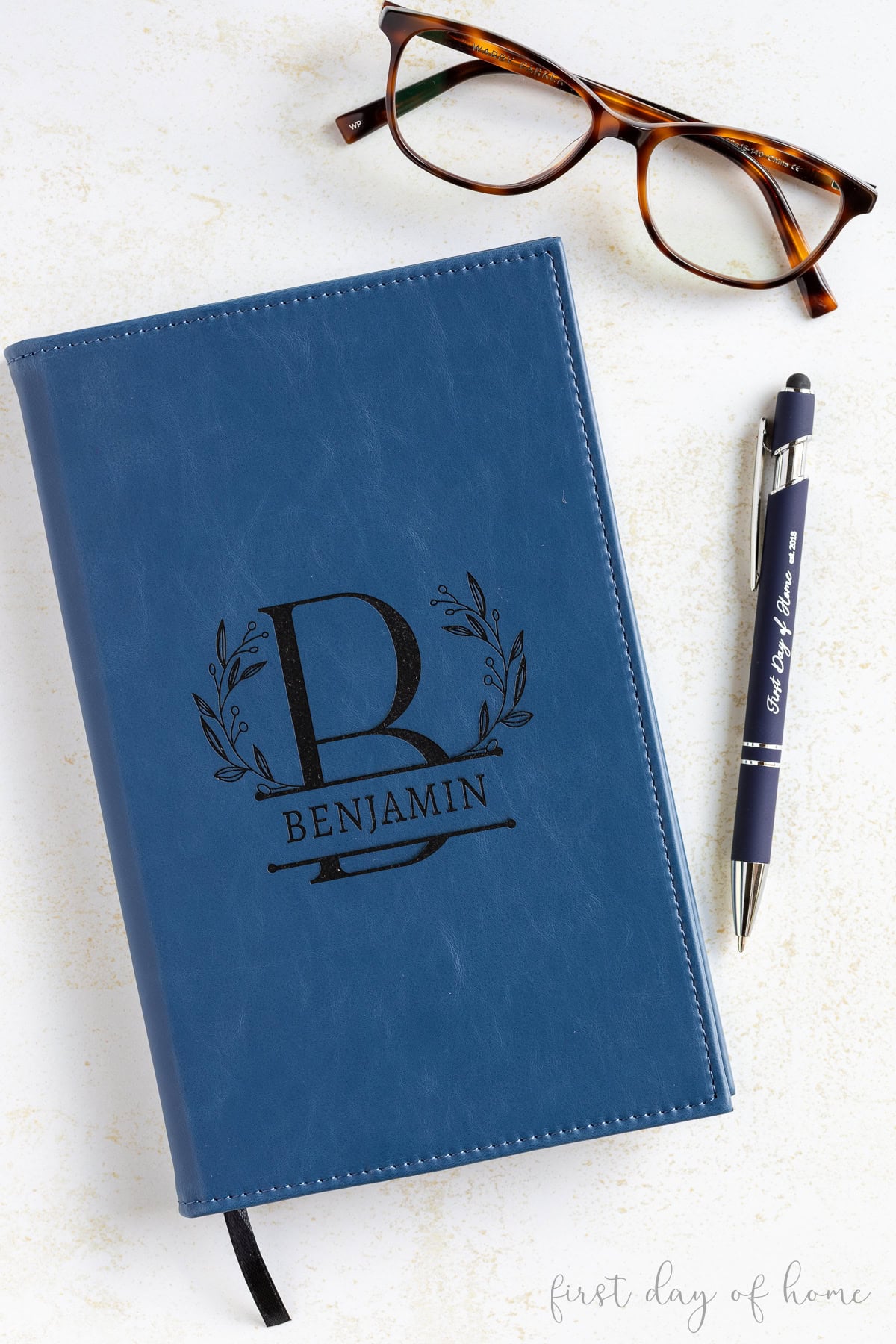 Laser engraved faux leather notebook and ballpoint pen shown with reading glasses.
