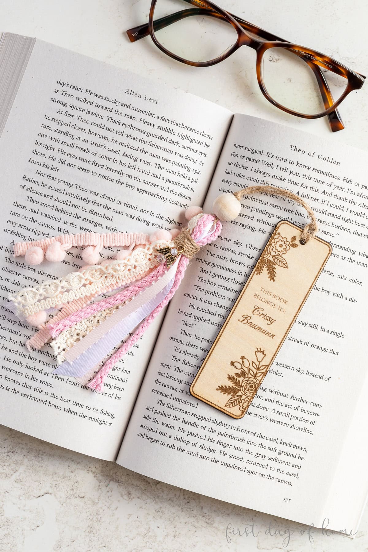 Laser engraved wooden bookmark with chunky tassel sitting on a book.