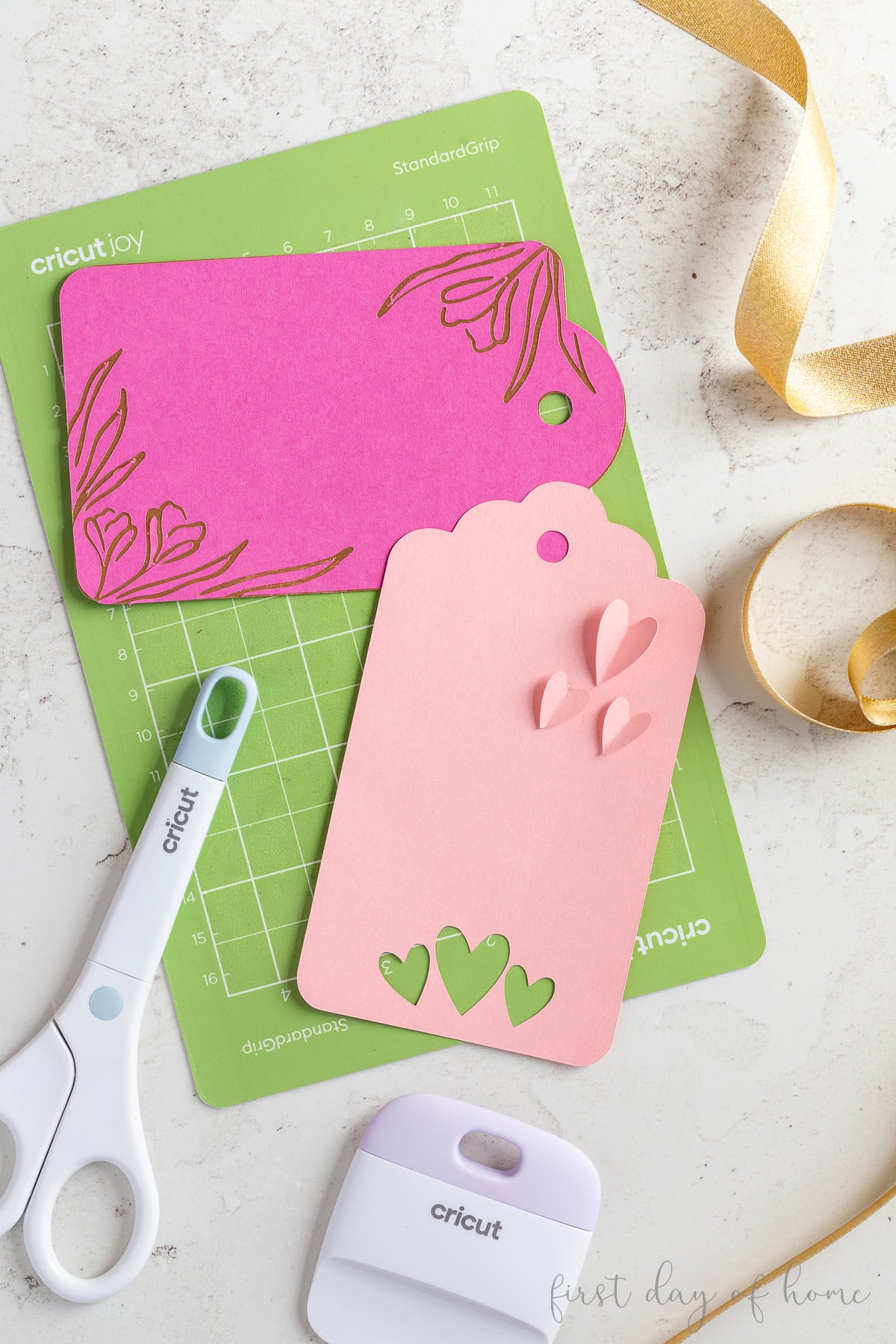 Two Cricut gift tags made with paper, shown with Cricut Joy mat, scissors, and scraper tool.