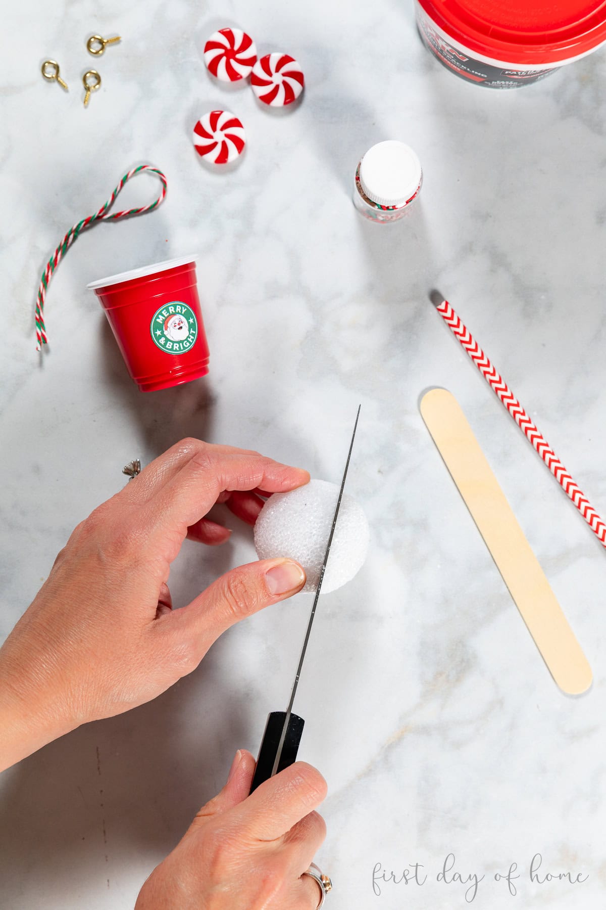 Cutting styrofoam ball to create DIY coffee cup ornament.