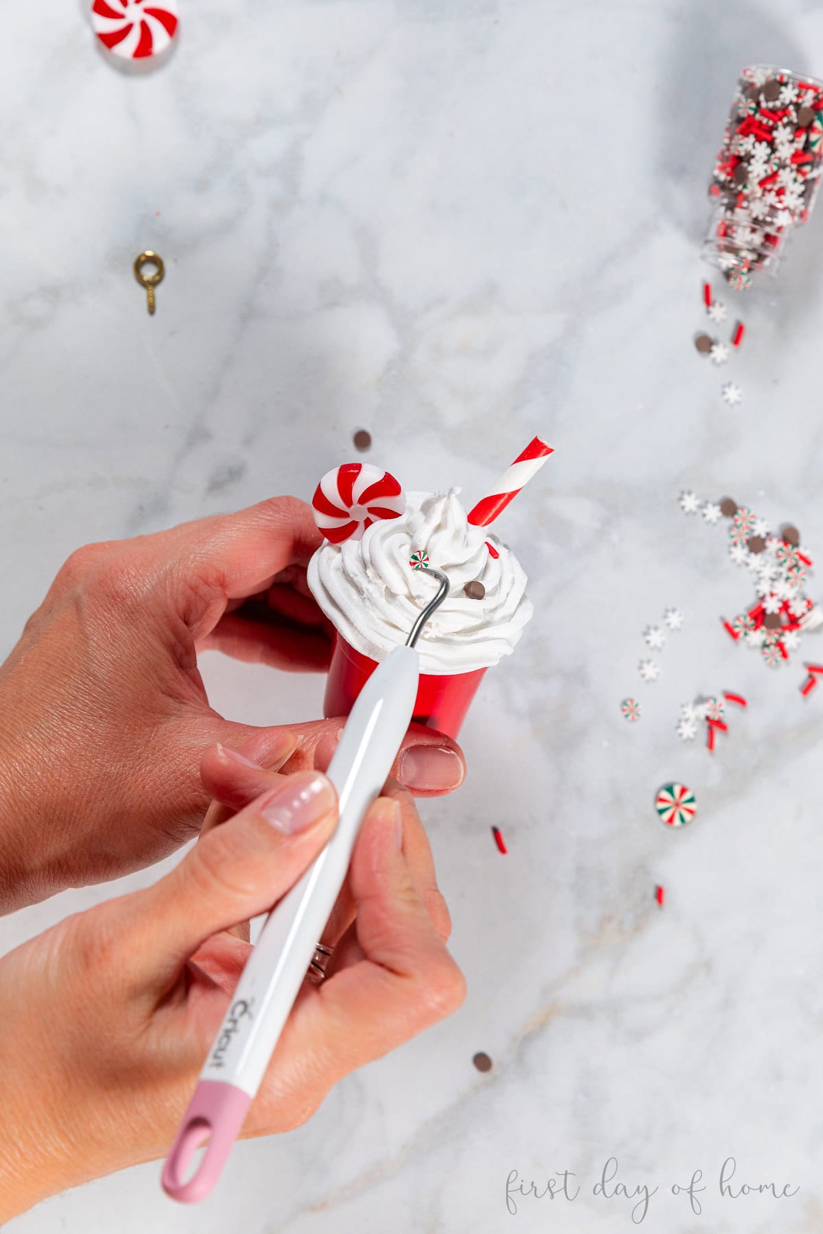 Adding faux sprinkles and a peppermint to a mini Starbucks coffee cup ornament.