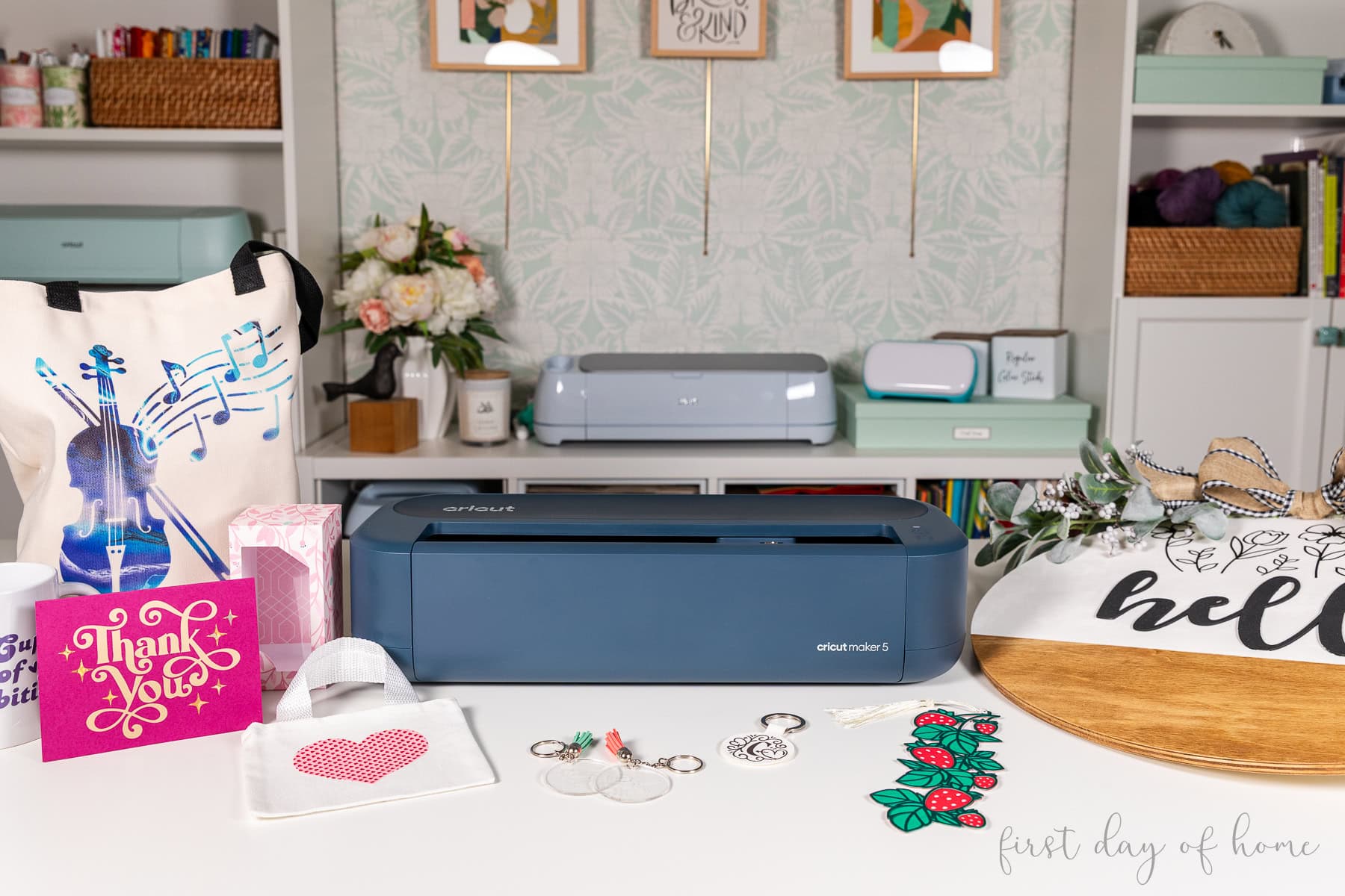 Cricut Maker 5 shown with various projects, including greeting cards, keychains, gift boxes, tote bags, and a wood sign.